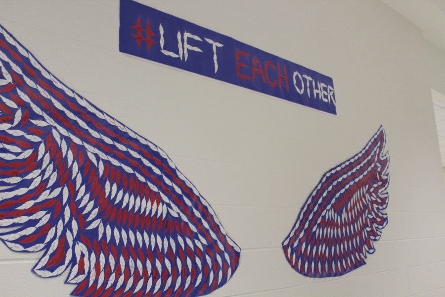 The mural, outside the cafeteria, displays wing-shaped papers on which students wrote the names of positive friends.